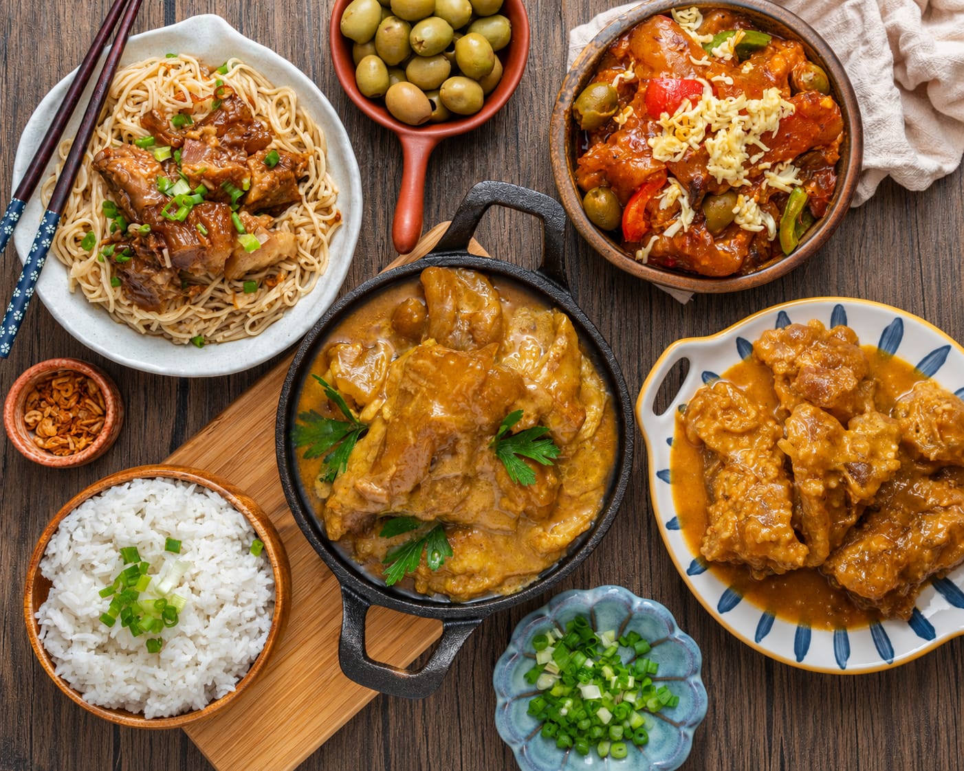 All four tendon flavors in one spread — HK style over noodles, kaldereta, curry in a cast-iron pot, and kare-kare, with steamed rice